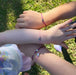 A mum and her daughters wearing pink and purple bracelets with heart charms