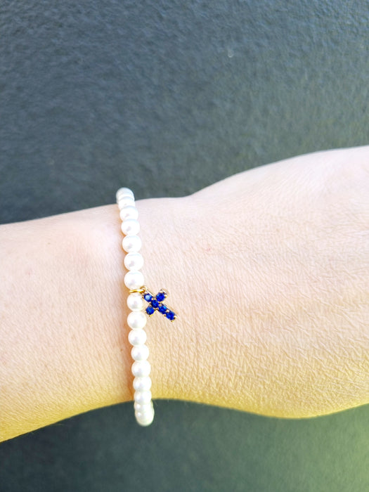 lady wearing slim pearl bracelet with blue cross