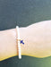 lady wearing slim pearl bracelet with blue cross