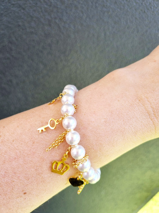 lady wearing white pearl bracelet with gold charms