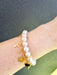 lady wearing white pearl bracelet with gold charms