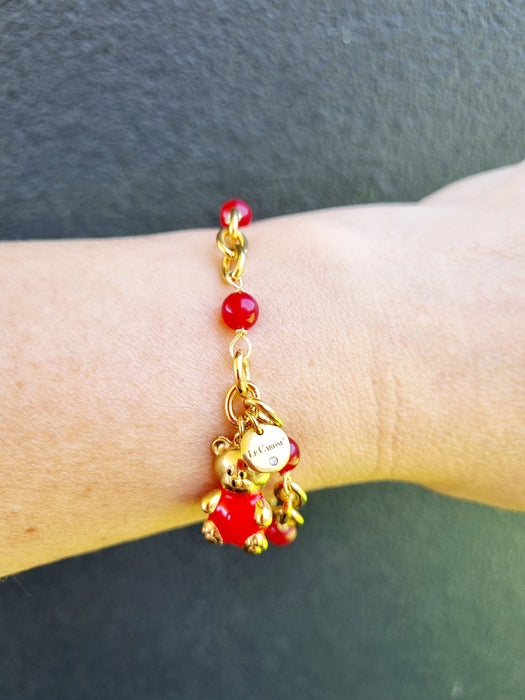 girl wearing gold bracelet with red bear charm