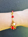 girl wearing gold bracelet with red bear charm