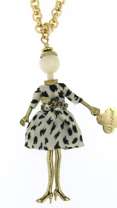 gold long chain necklace with doll pendant. Doll features spotted white dress, belt with heart, white head