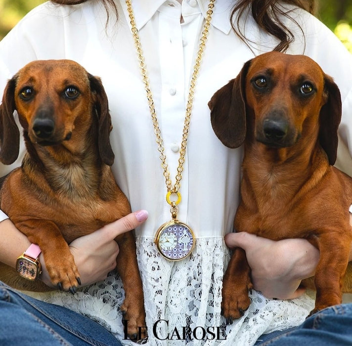 Lady holding 2 dogs wearing long gold chain necklace with clock pendant