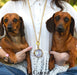 Lady holding 2 dogs wearing long gold chain necklace with clock pendant